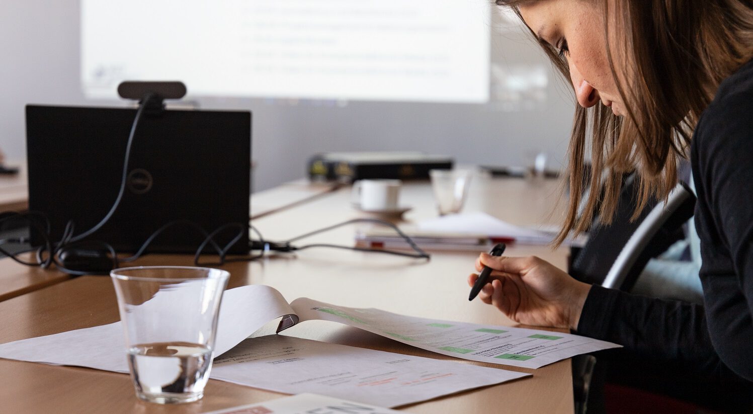 Ein Trainee ist bei einem Workshop und schreibt Notizen auf einem Zettel.