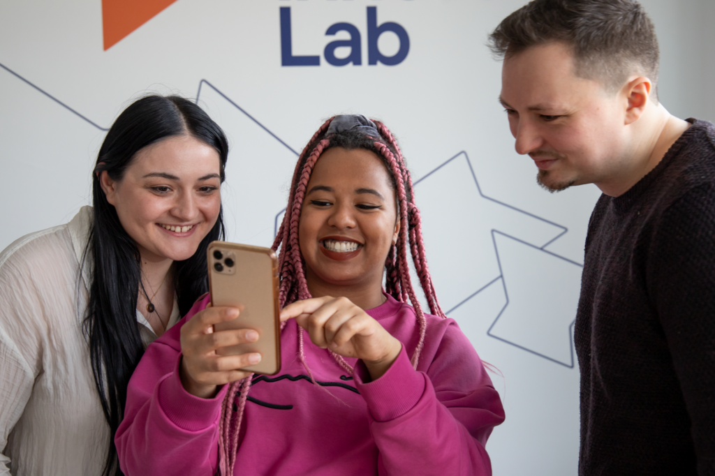 Lisa-Marie Idowu von dem Startup EdutainMe Media zeigt ihrem Team etwas auf ihrem Handy.