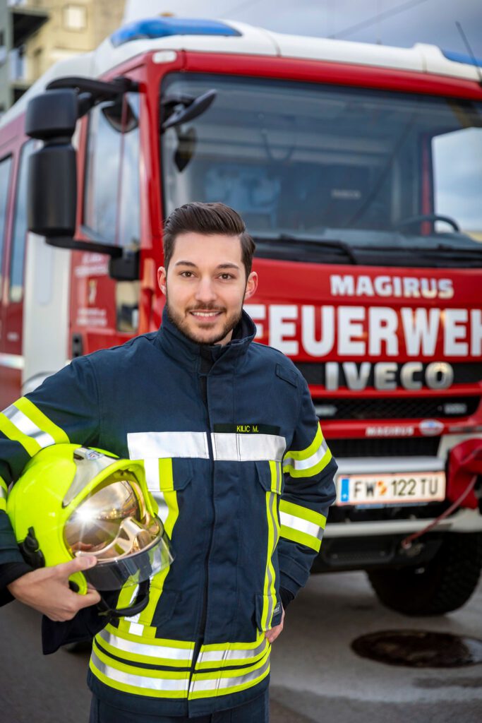 Marcel Kilic in Feuerwehruniform vor einem Feuerwehrwaagen.